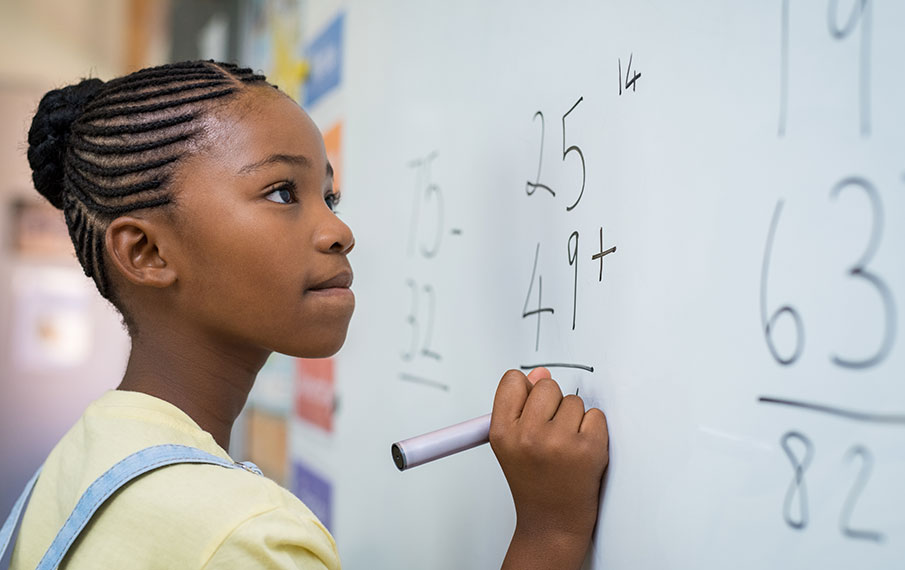 Student solving math problem at white board.